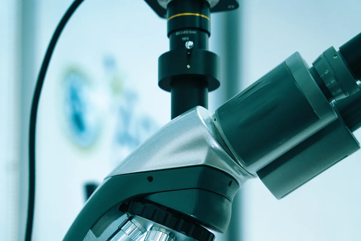 UK biomedical scientist examining samples under a microscope in a modern NHS hospital laboratory
