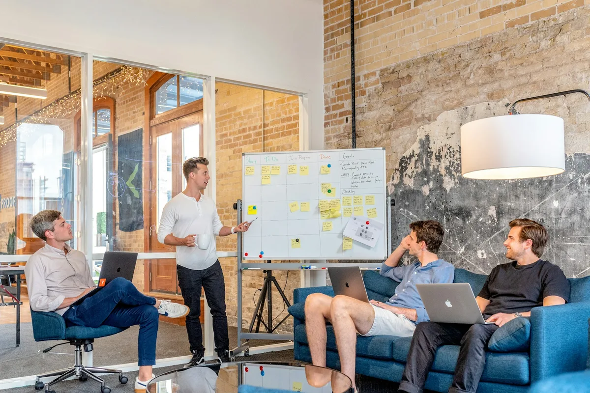 Business analyst presenting process flow diagrams on a whiteboard to a UK project team