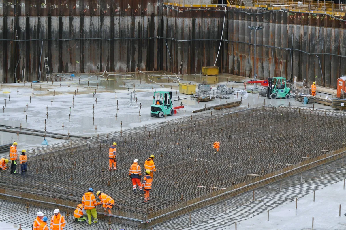 UK construction manager in a hi-vis vest reviewing plans with site staff on a major UK construction project