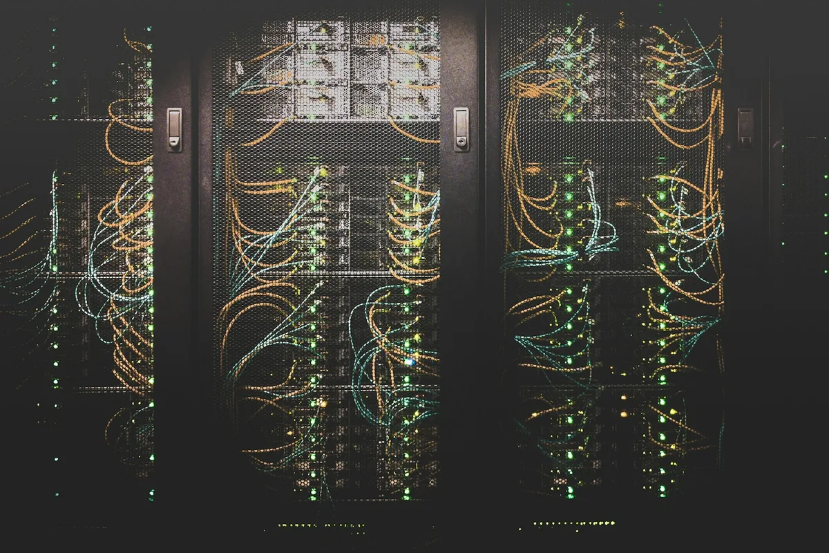 UK DevOps engineer monitoring cloud infrastructure dashboards and deployment pipelines on multiple monitors