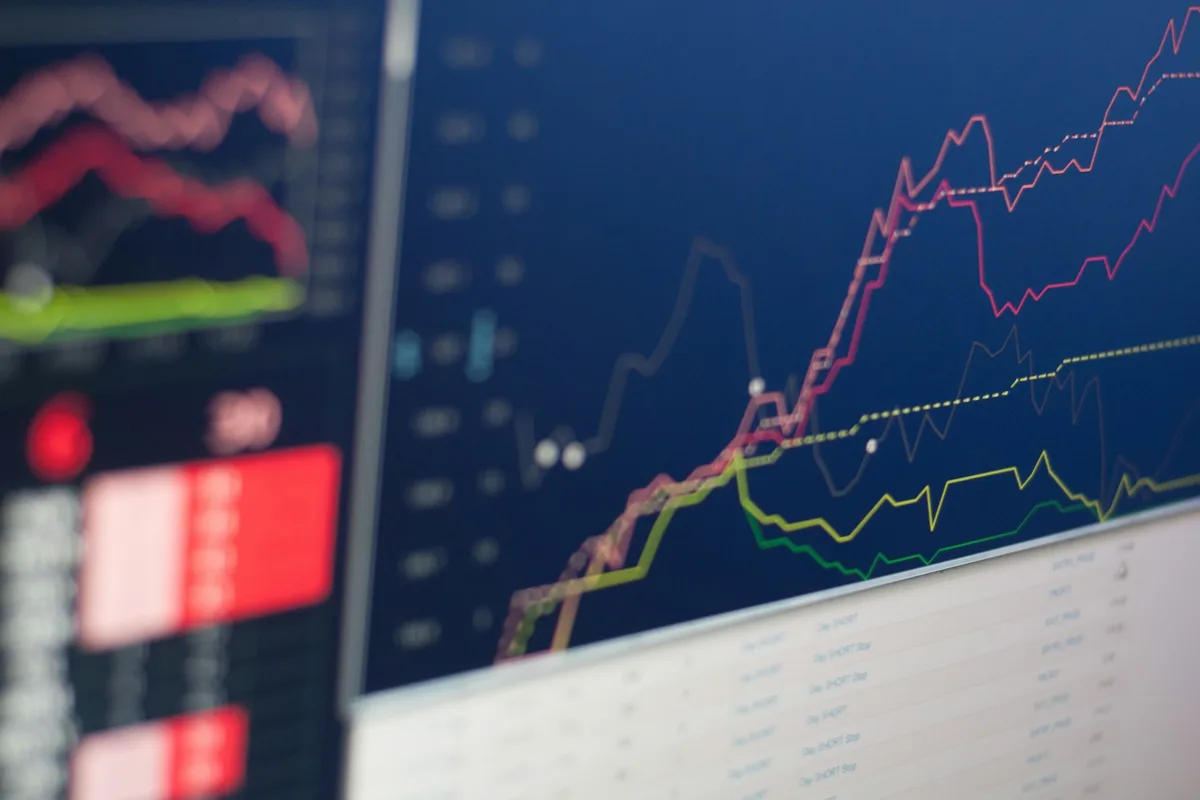 Financial analyst reviewing trading screens and market data dashboards in a modern London office