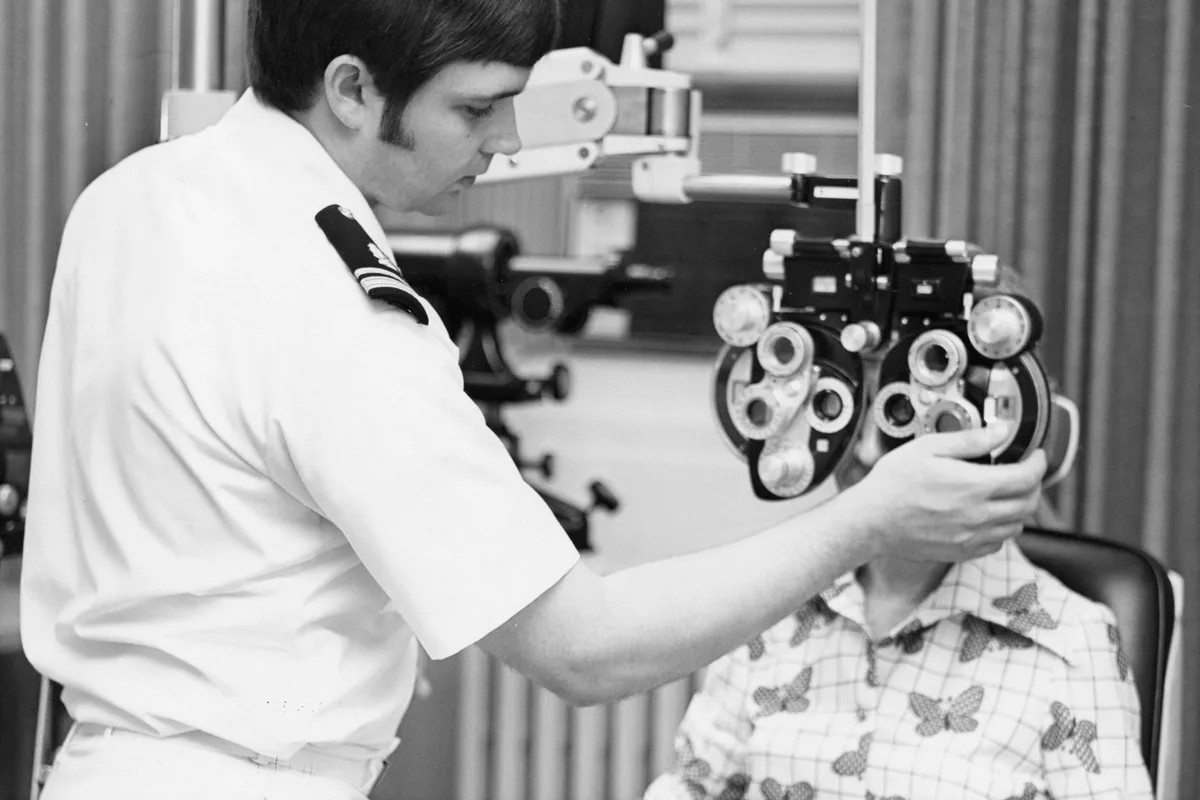 UK optometrist examining a patient's eyes with diagnostic equipment in a modern practice