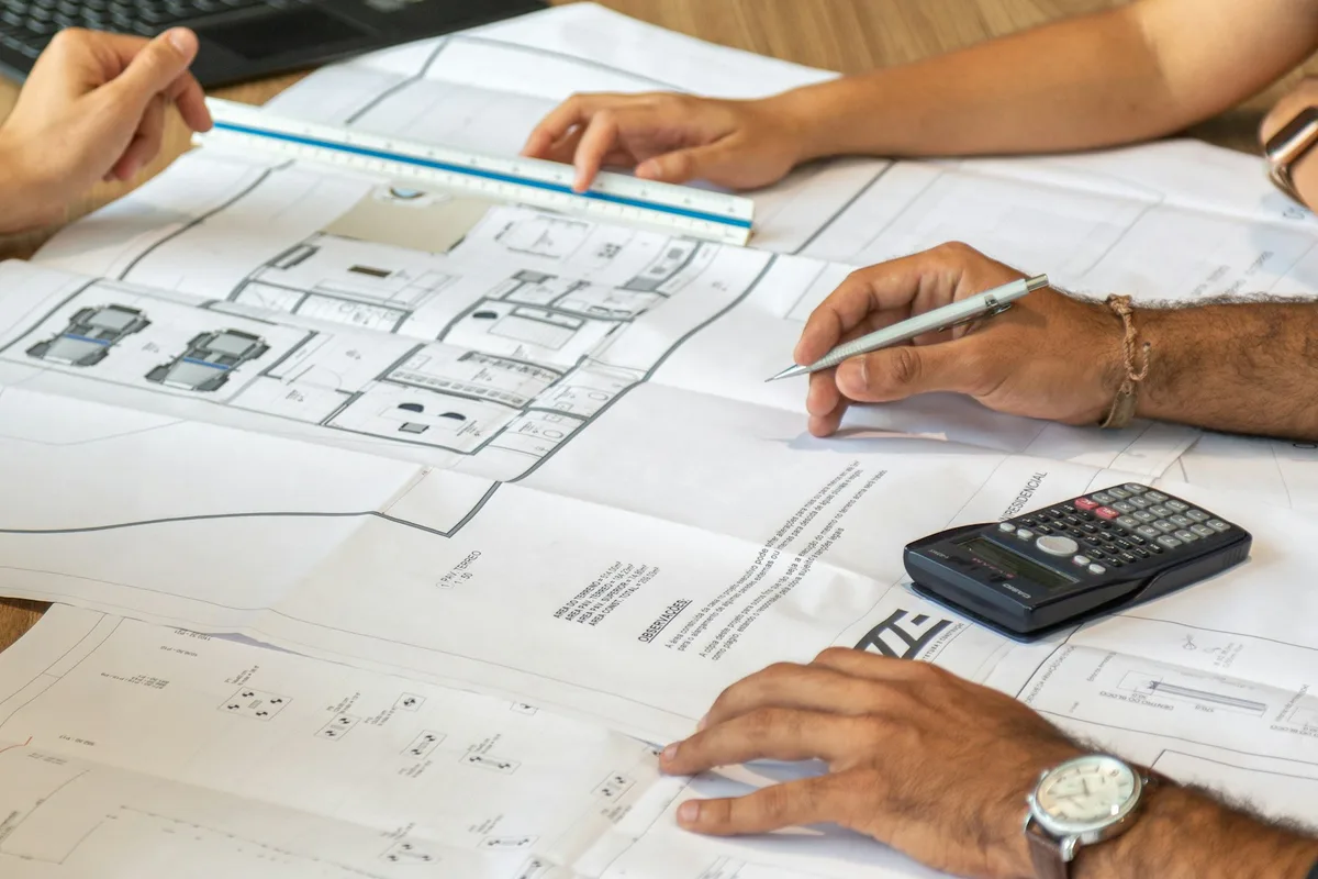 UK quantity surveyor reviewing tender documents and bill of quantities at a desk with construction plans