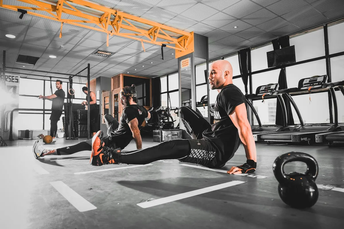 Athletes training in a strength-and-conditioning gym with kettlebells and treadmills